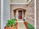 Inviting entryway with brick arch, dark door, and potted plants at 8509 Loxton Cir, Charlotte, NC 28214