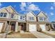 Three-unit townhome building with brick and stone accents, two-car garages, and landscaping at 6259 Tea Olive Dr # 178, Harrisburg, NC 28075