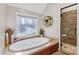 Relaxing bathroom with jetted tub, walk-in shower, and decorative window at 169 Rimmer Farm Rd, Troutman, NC 28166