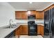 Kitchen features dark wood cabinets and black appliances at 545 Weavers Xing, Fort Mill, SC 29715