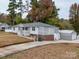 White ranch house with a covered porch, landscaped yard, and detached garage at 504 N Pine Ln, Wadesboro, NC 28170