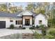 Modern farmhouse exterior with black accents, a front porch, and lush landscaping at 1524 Moss Creek Ln, Iron Station, NC 28080