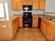 U-shaped kitchen with wood cabinets, black appliances, and tile flooring at 7374 Sun Dance Dr, Fort Mill, SC 29707