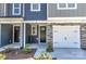 Townhome entry with gray siding, stone accents, and white garage door at 30 Woodsdale Se Pl, Concord, NC 28025