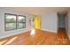 Bright living room with hardwood floors, large windows, and a yellow door at 9313 Trinity Rd, Charlotte, NC 28216