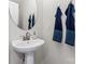 Clean powder room with pedestal sink, round mirror, and dark blue towels at 9232 Widden Way, Charlotte, NC 28269