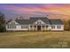 White farmhouse exterior with a gray roof, large front porch, and expansive lawn at 6980 Mooresville Rd, Kannapolis, NC 28081