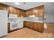 Kitchen with wood cabinets, white appliances, and view to living room at 124 Ashleigh Ct, Fort Mill, SC 29715