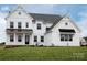 Two-story farmhouse with white siding, black accents, and a metal roof at Lot 41 Watercourse Way # Hawthorne, Belmont, NC 28012