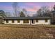 Ranch style home with white brick exterior, dark windows, and a gray roof at 3700 Pinecrest Dr, Gastonia, NC 28056