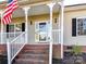 Front porch with white railings, brick steps, and an American flag at 827 Hathcock Glen Dr, Oakboro, NC 28129