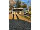 White RV with covered porch in wooded area at 204 Lake Tillery Trl, Mount Gilead, NC 27306
