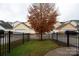 Small grassy backyard area with a tree and black fence at 10528 Royal Winchester Dr, Charlotte, NC 28277