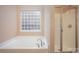 Bathroom with soaking tub, shower, and a block window at 10319 Dominion Village Dr, Charlotte, NC 28269