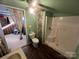 Small bathroom with shower, toilet, and vanity, with green walls and wood-look flooring, access to another room at 3217 Howe Dairy Rd, Gastonia, NC 28056