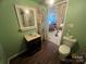 Small bathroom with vanity, toilet, and access to another room, green walls and wood-look flooring at 3217 Howe Dairy Rd, Gastonia, NC 28056