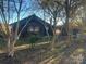 Dark-colored house with a simple design, surrounded by trees and a yard with leaf-covered ground at 3217 Howe Dairy Rd, Gastonia, NC 28056