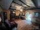 Living room with exposed wooden beams, a fireplace, and a view into the kitchen area at 3217 Howe Dairy Rd, Gastonia, NC 28056