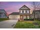 Charming two-story home with a two-car garage and landscaped front yard at sunset at 107 Meadowcreek Village Dr, Locust, NC 28097