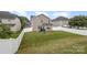 Large backyard with a sloped lawn and white vinyl fence at 13919 Highland Meadow Rd, Charlotte, NC 28273