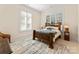 Well-appointed bedroom with wooden bedframe, patterned rug, and plantation shutters at 16424 Green Dolphin Ln, Cornelius, NC 28031