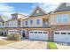 Tan, three-story townhome with white garage doors and dark brown front door at 4146 La Crema Dr, Charlotte, NC 28214