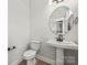 Powder room with pedestal sink, round mirror, and white toilet at 711 Hoke Ln, Davidson, NC 28036