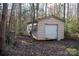 Tan storage shed with a roll-up door in a wooded area at 633 Weston Acres Rd, Fort Lawn, SC 29714