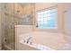 Bathroom featuring a soaking tub, glass-enclosed shower, and tiled walls at 6307 Cory Bret Ln, Charlotte, NC 28278