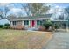 Brick ranch house with red door, carport, and landscaped lawn at 521 Colony Acres Dr, Charlotte, NC 28217