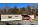 Tan manufactured home with a covered porch and wooded surroundings at 7486 Buff & Allen Rd, Hickory, NC 28602