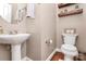 Half bathroom with a pedestal sink, toilet, and wooden shelves at 8002 Morehouse Dr, Waxhaw, NC 28173