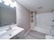 Clean and updated bathroom with white vanity, built-in shelving, and tub/shower combo at 208 Oakland Dr, Lowell, NC 28098