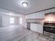 Bright and open kitchen with white cabinets, granite counters, and wood-look flooring at 208 Oakland Dr, Lowell, NC 28098