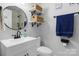 Clean bathroom with white vanity, floating shelves, and a round mirror at 8478 Rocky River Rd, Harrisburg, NC 28075