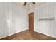 Empty bedroom with hardwood floors, white wood-paneled walls, and a ceiling fan at 7811 Casa Loma Rd, Charlotte, NC 28269