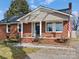 Quaint brick house with a covered porch, American flag, and landscaped yard at 2204 Emmanuel Church Rd, Conover, NC 28613