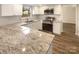 Modern kitchen featuring white cabinetry, stainless steel appliances, and granite countertops at 10907 Magenta Ln, Charlotte, NC 28262