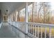Covered front porch with white railing, offering a relaxing view of the surrounding trees at 121 Pam Dr, Gastonia, NC 28056