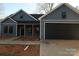 Newly constructed home featuring blue siding, a black garage door, and a covered porch at 635 E Ridge Rd, Salisbury, NC 28144