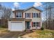 Two-story house featuring a beige exterior, red shutters, and a white garage door at 7 Riverside St, Lowell, NC 28098