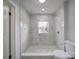 Modern bathroom with marble tile shower, pebble floor, and white fixtures at 221 Palmer St, Albemarle, NC 28001