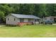 Tan one-story home with a large green yard, a gray roof, and shrubs at 309 Dover Dr, Bessemer City, NC 28016