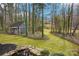 Wooded backyard with a gray outbuilding, landscaping, and a small pond at 14008 Creekside Dr, Matthews, NC 28105