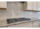 Gas cooktop with herringbone tile backsplash and granite countertops at 5348 Baker Ln, Lake Wylie, SC 29710