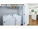 Bright laundry room with Whirlpool washer and dryer, and overhead shelving at 189 Calvin Creek Dr, Troutman, NC 28166