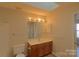 Bathroom with vanity, toilet, and mirror; features wood cabinets at 8121 #E Tremaine Ct, Charlotte, NC 28227