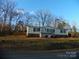 Single-wide mobile home with front deck, landscaping, and trees at 348 Shoreline Rd, New London, NC 28127