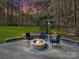 Stone fire pit with seating in backyard at dusk at 250 Kenway Loop, Mooresville, NC 28117