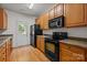 Kitchen with wood cabinets, black appliances, and door to backyard at 14752 Lions Paw St, Charlotte, NC 28273